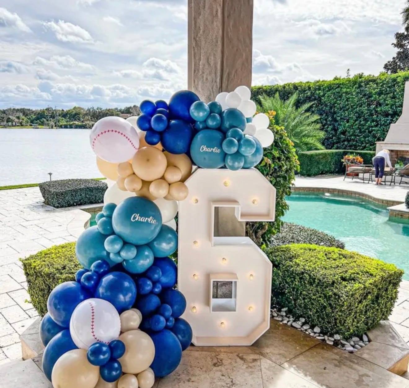 Marquee number 6 beside a balloon garland next to a pool